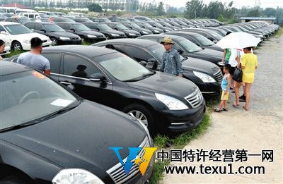 昨日，市民在山東棗莊一家拍賣公司場地上查看待拍賣公車。當(dāng)日，棗莊市103輛公車公開拍賣。新華社記者